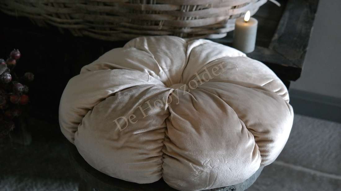 Kussen velvet rond beige van De Hooyzolder; zachte ronde vorm naast kaars op rustieke tafel.