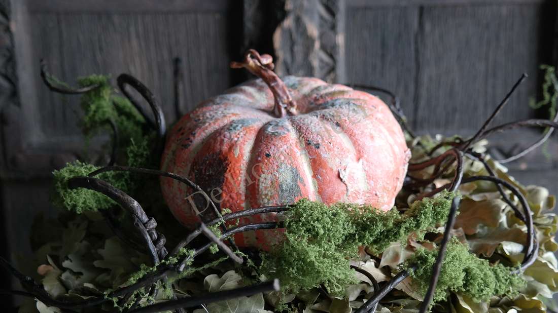Kalebas namaak oranje, maat M, omgeven door groen mos en takken.
