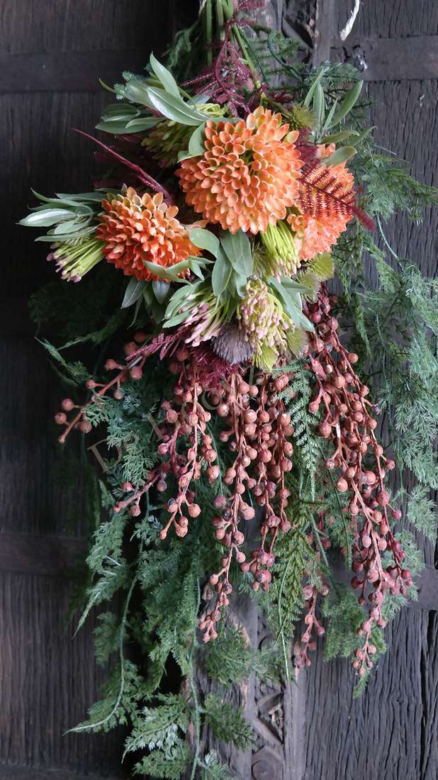 Hanger met kunstparagustak en groen blad, met oranje bloemaccenten en lange hangende bessen