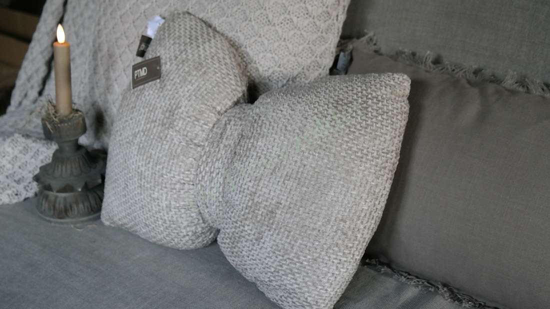 Strik kussen - velvet beige, twee gebreide kussens op een bank, PTMD-label zichtbaar.