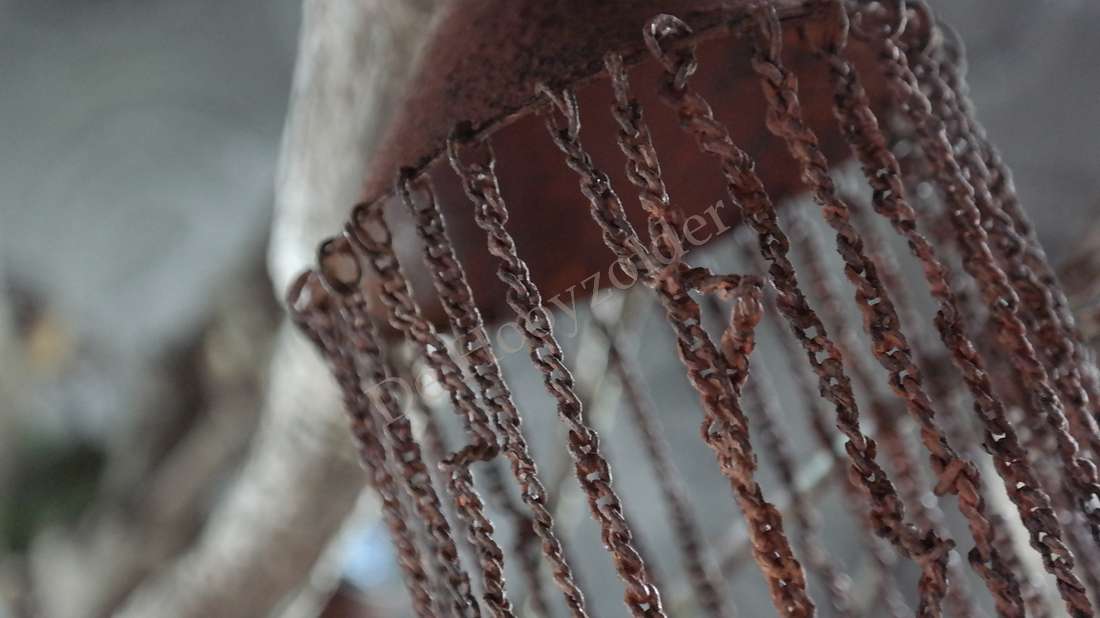 Munt draad hanger roestkleurig, metalen strengen hangen aan een ring, De Hooyzolder zichtbaar