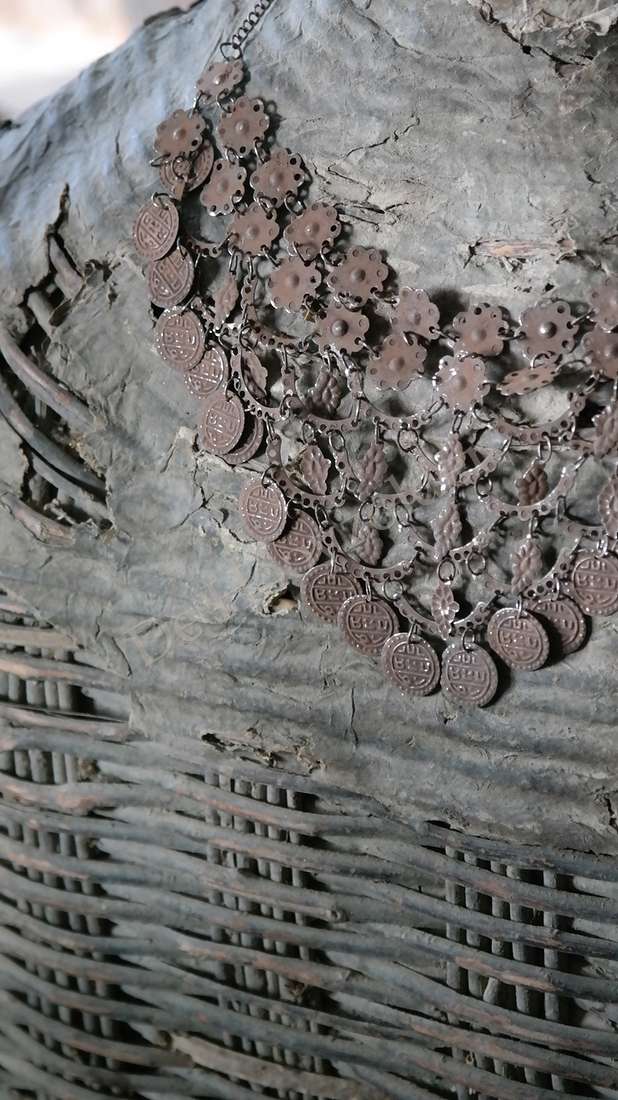 Sierketting met roestkleurige muntjes en metalen schakels, antieklook op grijze achtergrond
