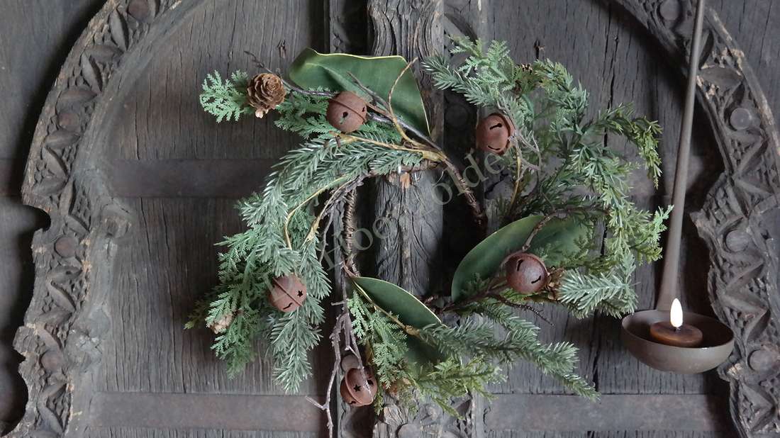 Krans Kerst dennenappel-bellen real touch met groene takken en dennenappels op een donkere houten deur
