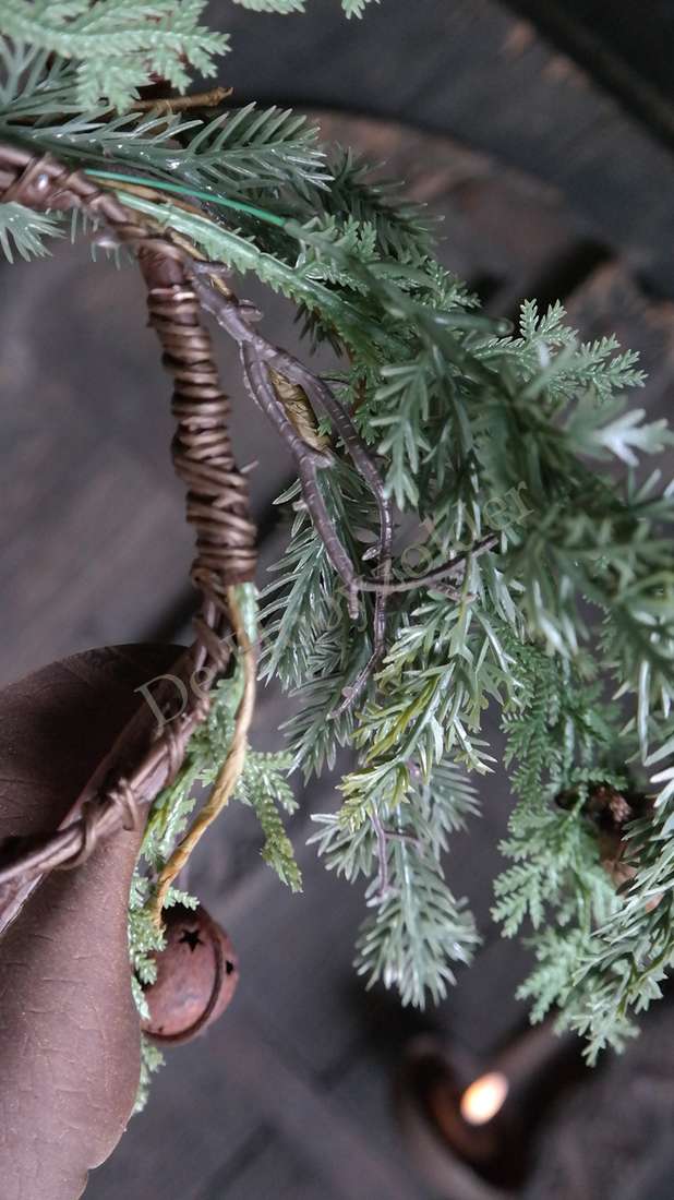 Krans met grijsgroene dennennaalden, gevlochten rieten ring en een kleine bel