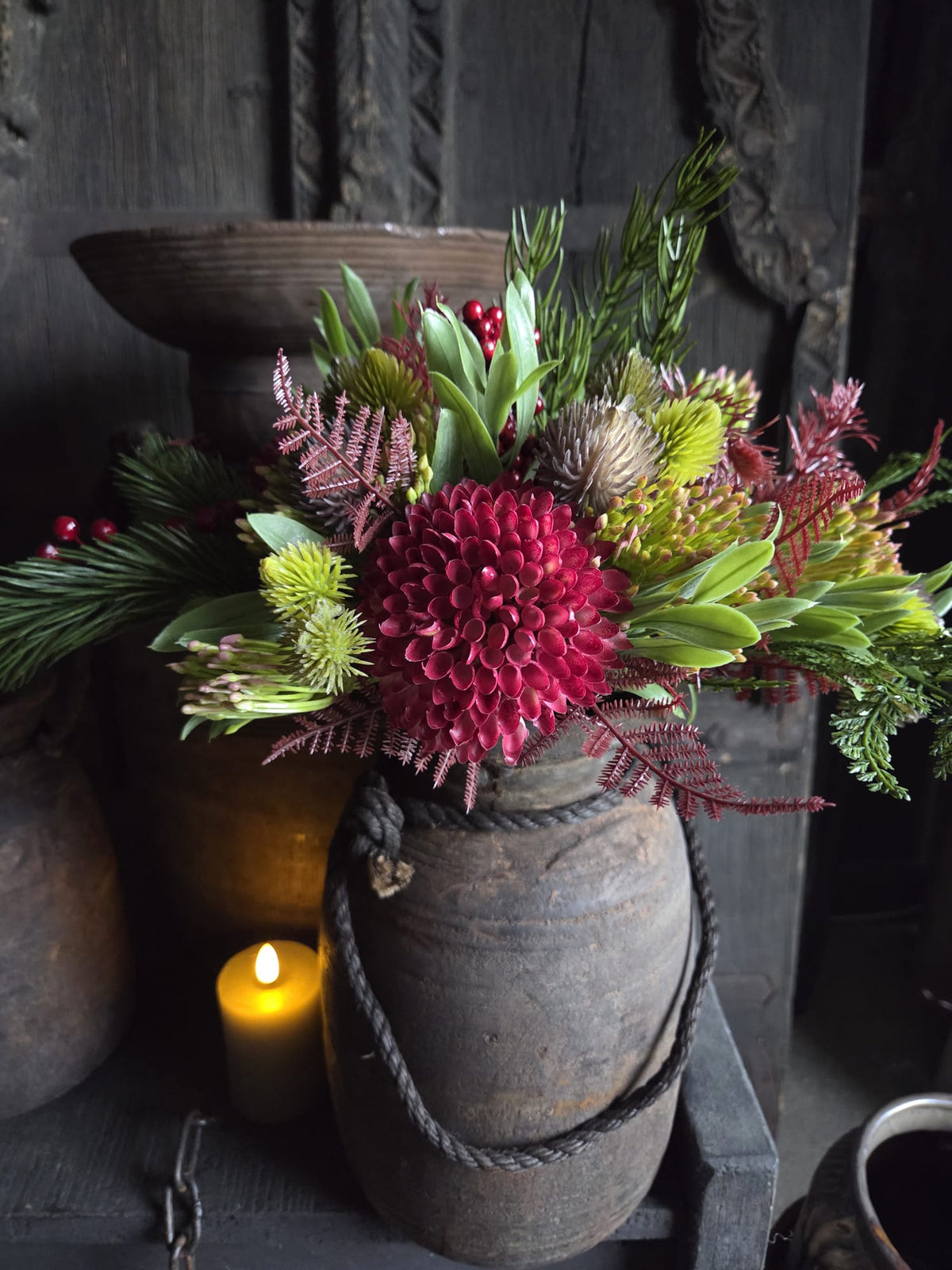 Boeket kant-en-klaar namaak Kerst S met rode en groene kunstbloemen in een grijze stenen vaas met touwhandvat