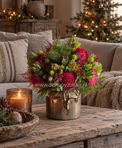 Boeket kant en klaar namaak Kerst van De Hooyzolder in metalen vaas met rode en groene kunstbloemen op houten tafel