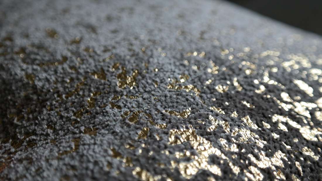 Kussen Flow in bruin en goud; close-up van textiel met gouden glitteraccenten.