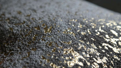 Kussen Flow in bruin en goud; close-up van textiel met gouden glitteraccenten.