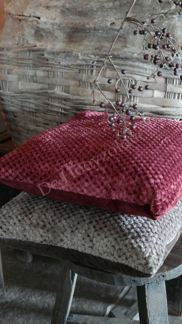 Twee kussens Rick fluffy: bordeaux en grijs met zachte, pluizige textuur, merk De Hooyzolder, op houten kruk.