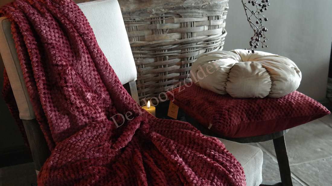Plaid Rick fluffy - bordeaux op stoel met beige kussen en ronde knoopkussen, De Hooyzolder.