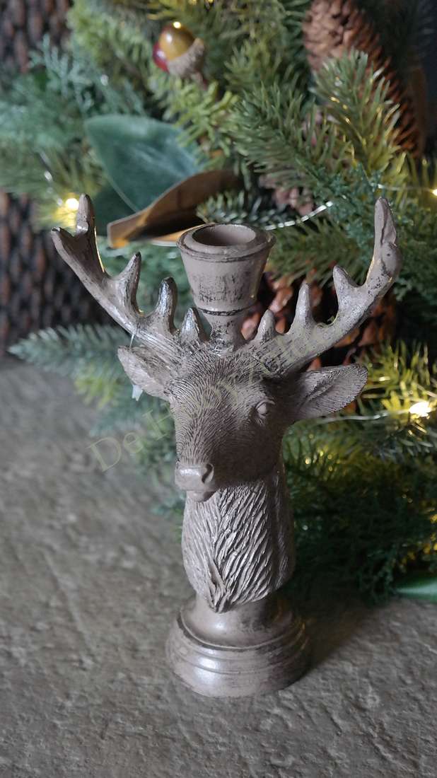 Kaarsenkandelaar Hertenkop van metaal in zilvergrijs, hoorns zichtbaar, achtergrond kerstboom met lampjes.