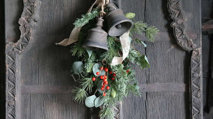 Kerstklok Ronja van hout, De Hooyzolder, met groene dennentakken, rode bessen en twee metalen belletjes hangend aan touw