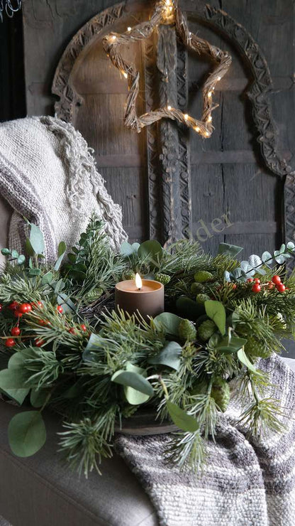 Kerstkrans 55 cm met eucalyptusbladeren en rode bessen rondom een brandende kaars