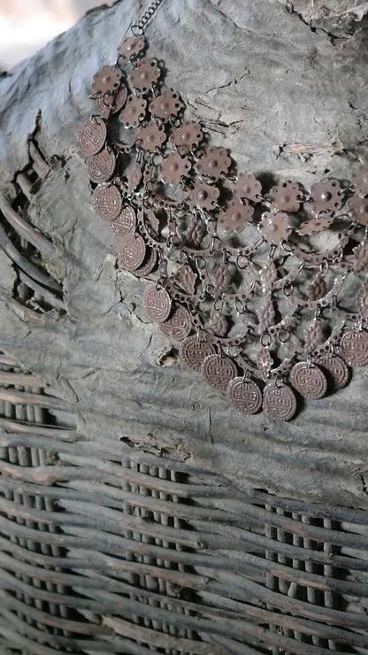 Sierketting met roestkleurige muntjes en metalen schakels, antieklook op grijze achtergrond
