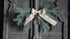 Hanger dennentakken real touch met strik, groene dennentakken en een burlap-strik op donker houten deur