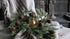 Kerstkrans met groene naalden, dennenappels en bruine bellen rondom glazen kaarsenhouder