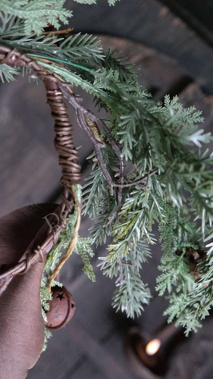 Krans met grijsgroene dennennaalden, gevlochten rieten ring en een kleine bel