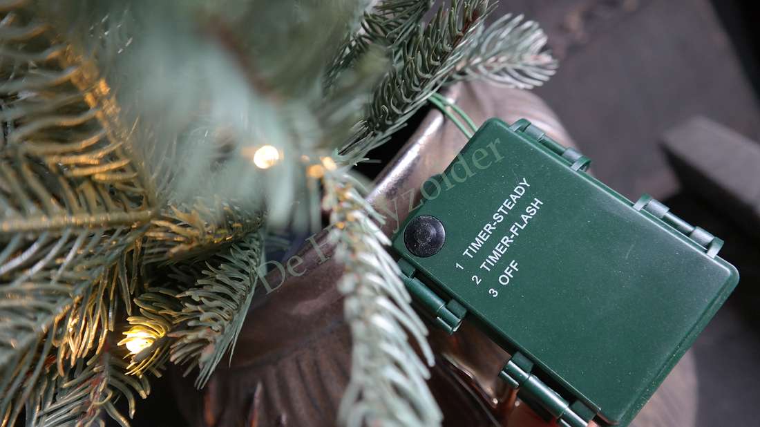 LED kerstboom Nordman real touch, groene controlebox met timerinstellingen tussen dennennaalden en LED-lampjes