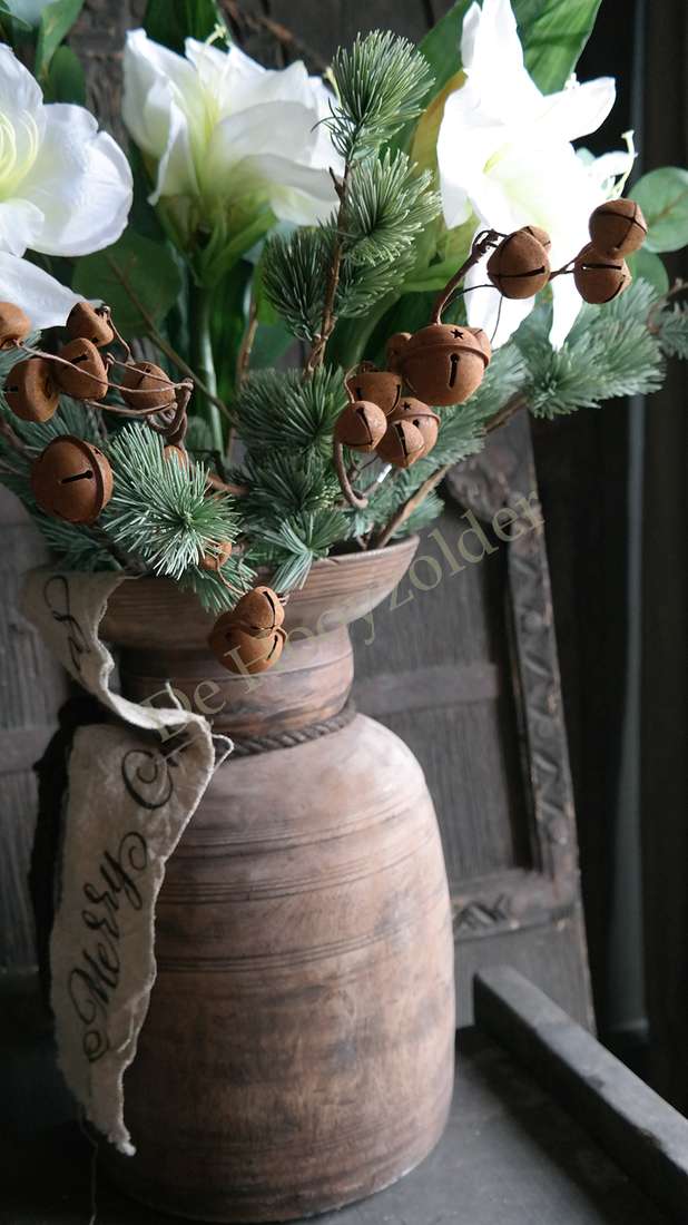 Boeket amaryllis wit in rustieke bruine vaas; groen takken en belletjes, merk De Hooyzolder zichtbaar