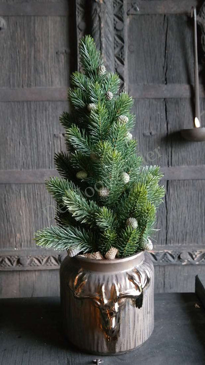 Kunstkerstboom Abies met LED-lampjes in een glanzende bruine vaas met hertenkop-ornament en dennenappels