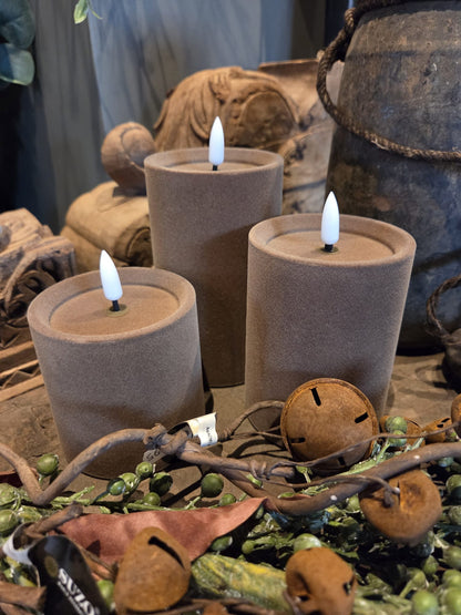 Drie taupe velvet stompkaarsen met witte LED-vlammen, flameless kaarsen in een rustieke decoropstelling