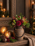 Kerstboeket namaak in rood en groen in keramische vaas met touwhandvat, op houten tafel met kaarsdecor.